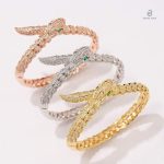 Bracelet serpent or rose, décoration avec yeux verts